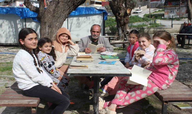 Eline kitabı alan muhtar, çocuklara örnek olmak için birlikte kitap okuyor